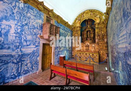Innenansicht der kleinen Kapelle mit reich geschnitzten, goldenen Holzaltar und dem berühmten Azulejo, blauen Fliesenwänden. In der Ermida de Nossa Senhora da Conceic Stockfoto
