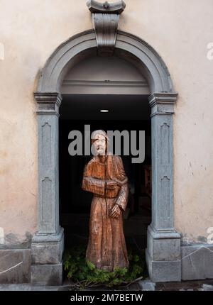 Sutrio, Italien - 29. Dezember 2022: Lebensgroße Holzskulptur eines Mannes unter einem Bogengang im Dorf Sutrio Stockfoto