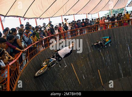 Mumbai, Indien. 08. Januar 2023. Ein Motorradfahrer im Maut ka Kuan (Brunnen des Todes) führt während der Erangal-Messe in Mumbai einen Stunt durch. Die Messe ist auch bekannt als St. Bonaventure Festmahl. Es markiert die Taufe oder Namenszeremonie von Jesus Christus und ist wie ein jährliches Treffen der ostindischen Gemeinschaft. Die Leute kommen und beten in der St. Bonaventure Kirche, die sich am Strand befindet, posten, dass sie Vergnügungsfahrten am Strand genießen und dort Essen und essen. Kredit: SOPA Images Limited/Alamy Live News Stockfoto