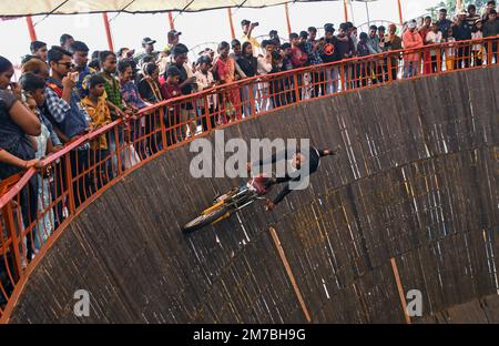 Mumbai, Indien. 08. Januar 2023. Ein Motorradfahrer im Maut ka Kuan (Brunnen des Todes) führt während der Erangal-Messe in Mumbai einen Stunt durch. Die Messe ist auch bekannt als St. Bonaventure Festmahl. Es markiert die Taufe oder Namenszeremonie von Jesus Christus und ist wie ein jährliches Treffen der ostindischen Gemeinschaft. Die Leute kommen und beten in der St. Bonaventure Kirche, die sich am Strand befindet, posten, dass sie Vergnügungsfahrten am Strand genießen und dort Essen und essen. Kredit: SOPA Images Limited/Alamy Live News Stockfoto