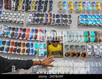 Mumbai, Indien. 08. Januar 2023. Ein Junge, der eine Sonnenbrille ausprobiert, überprüft sich im Spiegel während der Erangal-Messe in Mumbai. Die Messe ist auch bekannt als St. Bonaventure Festmahl. Es markiert die Taufe oder Namenszeremonie von Jesus Christus und ist wie ein jährliches Treffen der ostindischen Gemeinschaft. Die Leute kommen und beten in der St. Bonaventure Kirche, die sich am Strand befindet, posten, dass sie Vergnügungsfahrten am Strand genießen und dort Essen und essen. Kredit: SOPA Images Limited/Alamy Live News Stockfoto