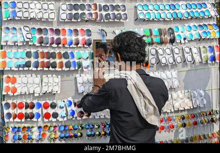 Mumbai, Indien. 08. Januar 2023. Während der Erangal-Messe in Mumbai blickt ein Straßenhändler, der Sonnenbrillen verkauft, in den Spiegel. Die Messe ist auch bekannt als St. Bonaventure Festmahl. Es markiert die Taufe oder Namenszeremonie von Jesus Christus und ist wie ein jährliches Treffen der ostindischen Gemeinschaft. Die Leute kommen und beten in der St. Bonaventure Kirche, die sich am Strand befindet, posten, dass sie Vergnügungsfahrten am Strand genießen und dort Essen und essen. (Foto: Ashish Vaishnav/SOPA Images/Sipa USA) Guthaben: SIPA USA/Alamy Live News Stockfoto