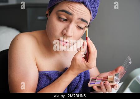 Junge Geschlecht Flüssigkeit Person Mann Anwendung Lidschatten. Stockfoto