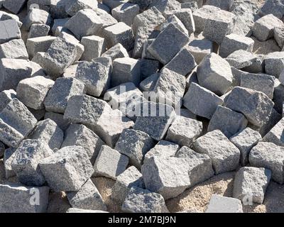 Kopfsteinpflasterhintergrund, Baumaterial aus Pflasterstein auf der Baustelle Stockfoto