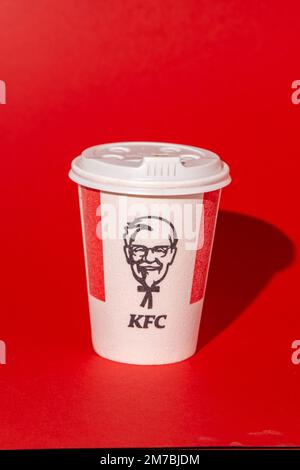 Rotes weißes KFC-Glas für Kaffee, Kakao, Tee auf rotem Hintergrund. Heißes Getränk zum Mitnehmen. Logo von Kentucky Fried Chicken. Fast-Food-Restaurant. Harland Sanders Ukraine, Kiew - 10. November 2022. Stockfoto