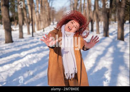 Die fette kaukasische Frau tanzt im Winter auf einem Spaziergang im Park. Stockfoto