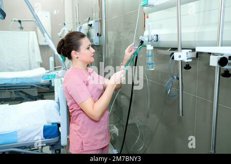 Arztin, die auf der Intensivstation des Krankenhauses mit medizinischen Geräten arbeitet Stockfoto