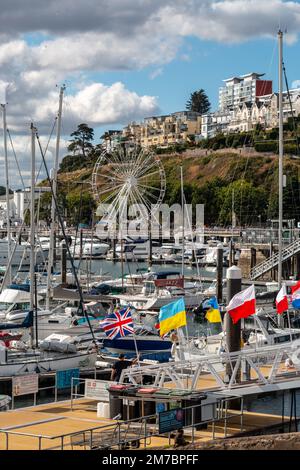 Ein Blick über den Hafen von Torquay mit Flaggen aus vielen Ländern. Im Hintergrund befindet sich das englische Riviera Wheel. Stockfoto