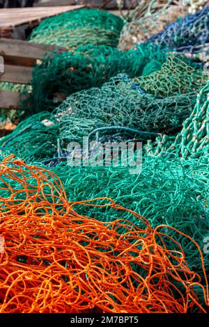 Ein Wirrwarr aus leuchtend orangefarbenen und grünen Fischernetzen im Hafen von Torquay, Devon, Großbritannien. Stockfoto