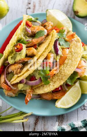 Mexikanische Tacos mit Garnelen, Guacamole und Gemüse auf einem Holztisch Stockfoto