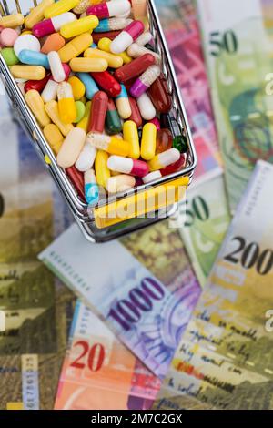 Bunte Pillen in einem Wagen mit Schweizer Franken, ausgeschnitten Stockfoto
