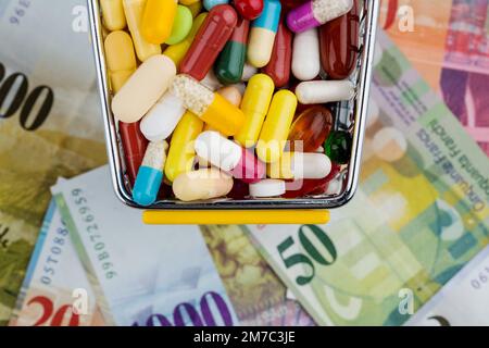 Farbenfrohe Pillen in einem Trolley mit Schweizer Franken Stockfoto