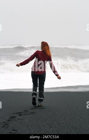 Rothaarige Frau, die entlang des nördlichen Strands spaziert und malerische Fotos macht Stockfoto