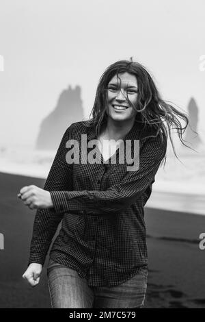 Aus nächster Nähe glückliche Touristen am Strand von Reynisfjara monochrome Porträtfotos Stockfoto