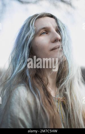 Nahaufnahme wunderschöne Frau mit langen grauen braunen Haaren, die auf ein Porträtbild schaut Stockfoto