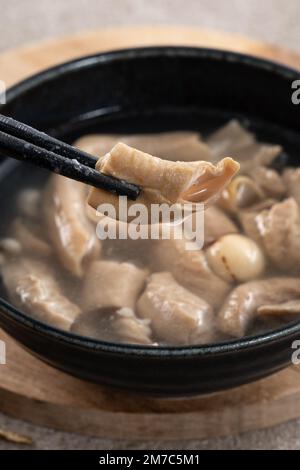 Four Tonics Suppe. Köstliches hausgemachtes taiwanesisches traditionelles chinesisches Kräutergericht mit Kräutern, Schweinedärm auf grauem Tischhintergrund Stockfoto