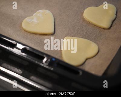 Hausgemachte herzförmige Kekse auf einem Backblech Stockfoto