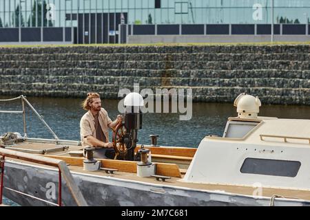 Weitwinkelblick auf attraktiven jungen Mann Segelboot auf dem Fluss, Kopierraum Stockfoto