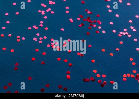 Konfetti in Herzform auf dunkelblauem Hintergrund, Valentinstag-Konzept Stockfoto
