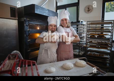 Porträt eines Mannes mit Down syndrom und seines Kollegen in der Bäckerei. Konzept der Integration von Menschen mit Behinderungen in die Gesellschaft. Stockfoto