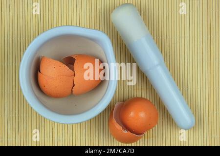 Eierschale. Schale von Eiern auf einer Platte, die zur Zugabe zum Kompost verarbeitet wird. Strohhintergrund. Stockfoto