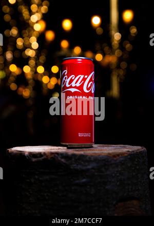 Belgrad, Serbien - 5. Januar 2023: Coca-Cola-Dose auf Holzholz mit Weihnachtsbeleuchtung und Dekoration im Hintergrund bei Nacht in Belgrad, Ser Stockfoto