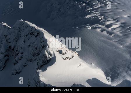 Ein Luftblick über die Eisfelder der südlichen Alpen in Neuseeland mit einem Bergkamm, interessanten Mustern und Gletscherspalten. Stockfoto