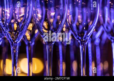 Saubere Weingläser in der Nachtbar, die in Neonfarben leuchten. Stockfoto