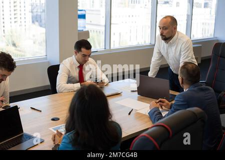 Gruppe von jungen Geschäftsleuten arbeiten und kommunizieren, während am Schreibtisch sitzen zusammen mit Kollegen sitzen. Business Meeting Stockfoto