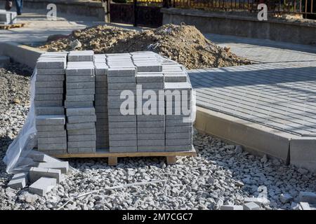 Der Bau von Straßenbauarbeiten Landschaftsbaufertiger zur Vorbereitung der Verlegung von Graubetonsteinen Stockfoto