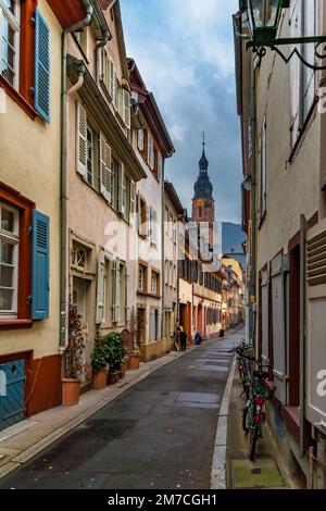 Schöner Blick auf eine enge Gasse, die zur berühmten Heiliggeistkirche führt, die sich auf dem Marktplatz in der Altstadt von Heidelberg befindet... Stockfoto