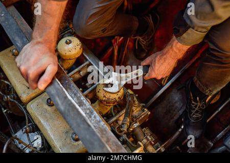 Nahaufnahme eines unbekannten Arbeiters, der den Motor repariert und die Schrauben mit einem Metallschlüssel gelöst hat, Kopierraum Stockfoto