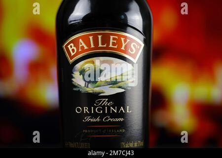 KIEW, UKRAINE - 4. MAI 2022 Baileys Original-Alkoholflasche auf Holztisch mit rotem Kamin im Hintergrund. Elite-Alkoholproduktion Stockfoto