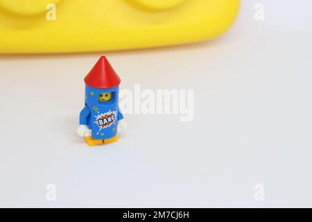 Eine lego-Minifigur in einem Raketenkostüm mit einem riesigen gelben Block im Hintergrund, isoliert auf Weiß Stockfoto