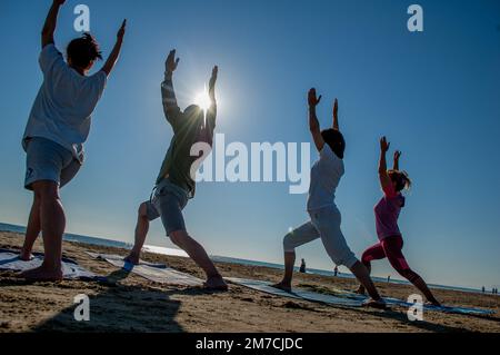 Rimini Italien August 7 2016: Eine Gruppe von Menschen, die bei Sonnenaufgang am Strand Gymnastik machen Stockfoto