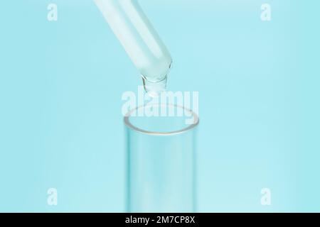 Flüssigkeitstropfen von der Laborglaspipette auf das Reagenzglas. Das Konzept der chemischen Industrie und die Arbeit im Labor. Stockfoto