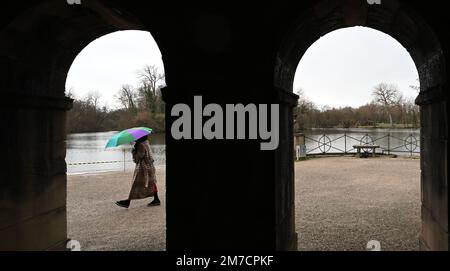 Ludwigsburg, Deutschland. 09. Januar 2023. Eine Frau mit Sonnenschirm läuft vor dem See vor dem Schloss am Monrepoes See. Kredit: Bernd Weißbrod/dpa/Alamy Live News Stockfoto