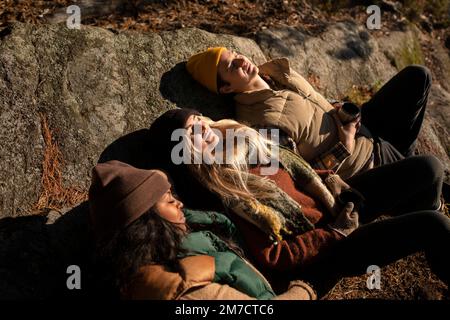 Blick aus der Vogelperspektive auf männliche und weibliche Freunde, die sich an sonnigen Tagen auf dem Felsen entspannen Stockfoto