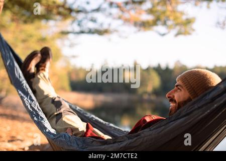 Ein glücklicher Männertag, träumt und entspannt in einer Hängematte im Wald Stockfoto