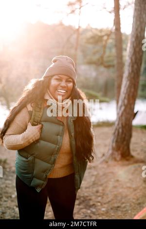 Porträt einer glücklichen jungen Frau, die im Wald steht Stockfoto