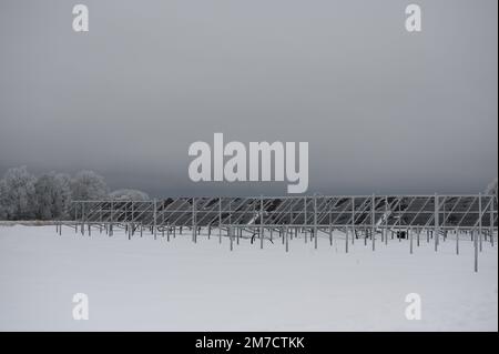 Sonnenkollektoren auf dem Feld an einem grauen, kalten Wintertag in ländlicher Landschaft Stockfoto