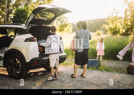 Sohn und Mutter laden Gepäck aus dem Kofferraum Stockfoto