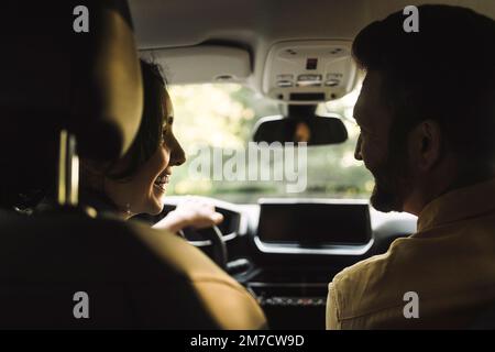 Glückliche Frau, die einen Mann im Auto ansieht Stockfoto