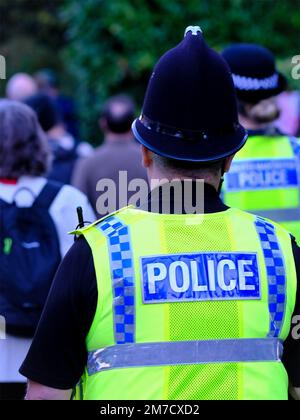 Polizist zeigt das Wort Polizei auf Jacke und trägt einen traditionellen Helm Stockfoto