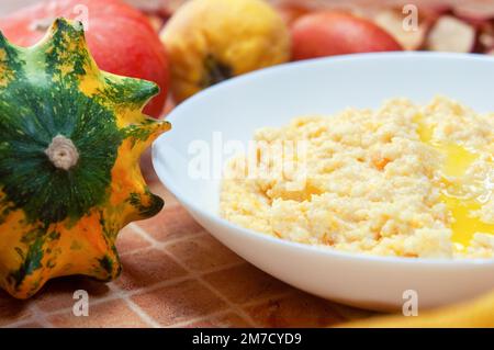 Nahaufnahme von Kürbisbrei mit Hirse, serviert in einer weißen Schüssel, selektiver Fokus, horizontaler Schuss. Stockfoto