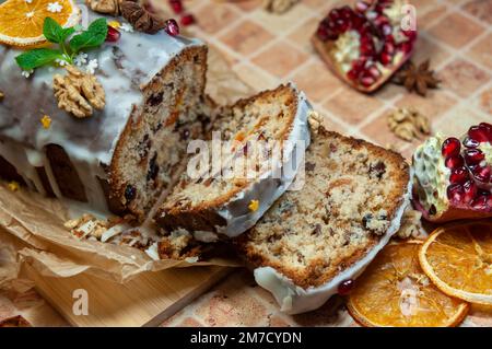Weihnachtsstollen mit kandierten Früchten und getrockneten Früchten auf Pergament. Stollen: Traditionelles deutsches Brot, das in der Weihnachtszeit gegessen wird. Stollen auf w Stockfoto