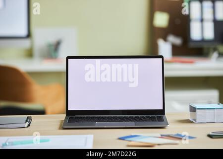 Hintergrundbild eines offenen Laptops mit weißem Bildschirmmock auf dem Schreibtisch in gemütlicher Büroumgebung, Kopierbereich Stockfoto