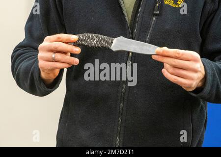 Düsseldorf, Deutschland. 09. Januar 2023. Ein Schauspieler präsentiert ein Praxismesser für die Ausbildung von Polizeibeamten, NRW Innenminister Herbert Reul besucht das Düsseldorfer Polizeiausbildungszentrum und erfährt von der Gefahr von Messerangriffen auf Polizeibeamte im Düsseldorfer Polizeihauptquartier, 27. April 2021 Kredit: dpa/Alamy Live News Stockfoto
