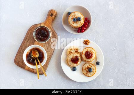 Frühstück am Valentinstag mit kleinen Pfannkuchen, herzförmiger Marmelade und frischen Beeren, Blick von oben Stockfoto