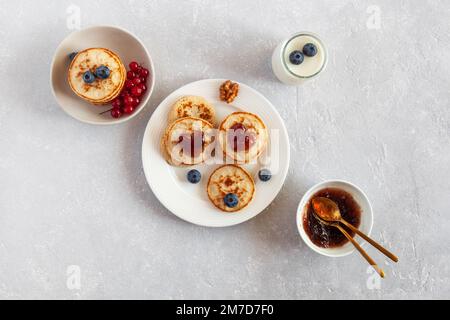 Joghurt und Mini-Pfannkuchen dekoriert mit herzförmiger Marmelade und frischen Beeren, Valentinstag-Frühstücksidee, Draufsicht Stockfoto